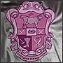 Фото вышивки фиолетового герба на серебряном чехле для подушки